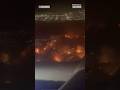 Video shot from a plane flying over Los Angeles shows the path of fast-moving wildfires.